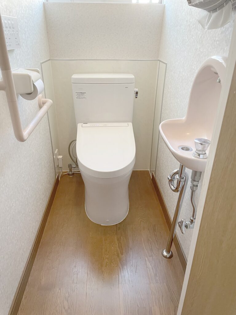 手洗器はそのまま使用。トイレの取替えと後方棚を撤去し、パネルを貼りました。